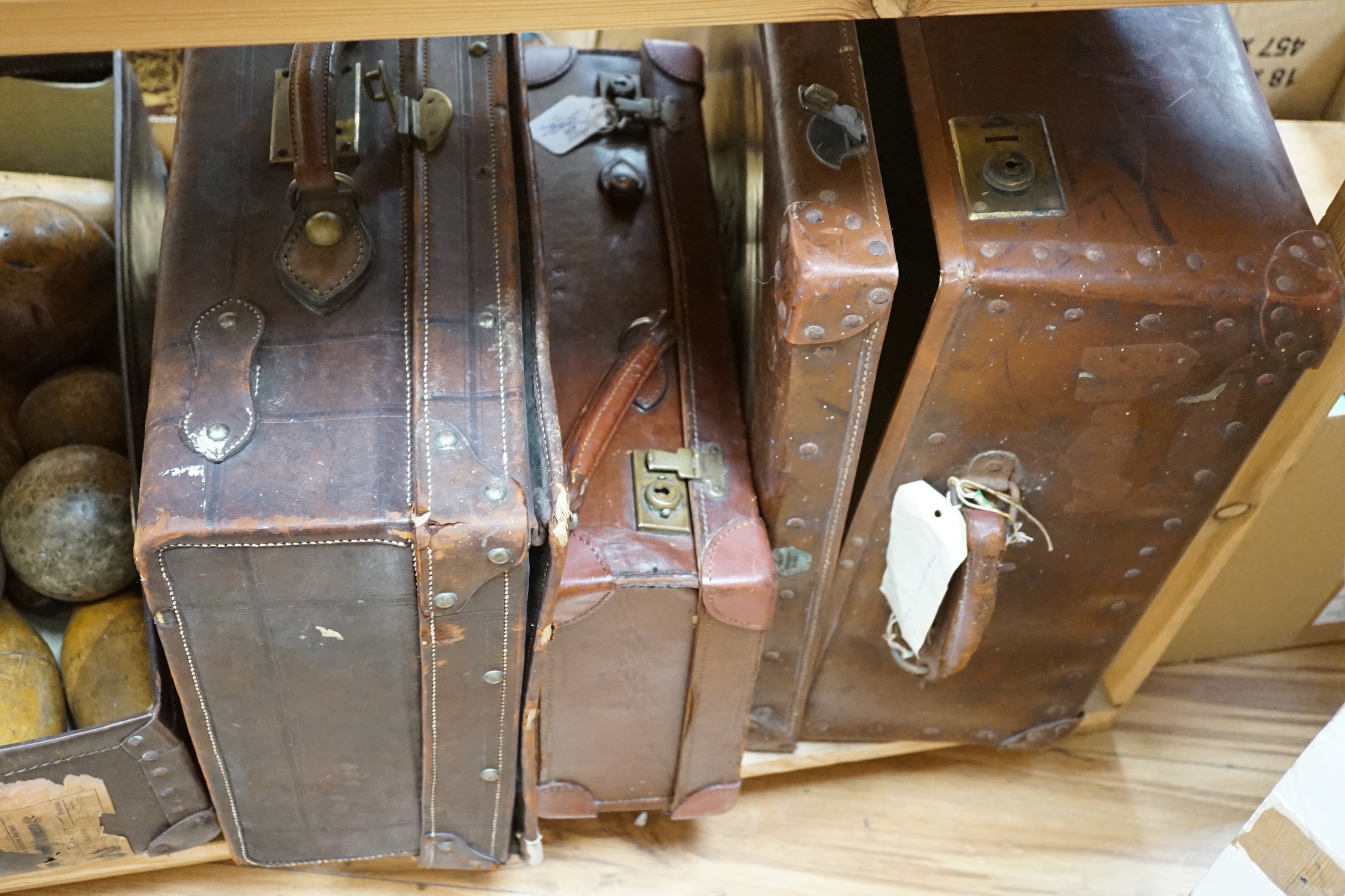 Seven vintage leather suitcases and a leather writing box (locked), the largest 60cm wide